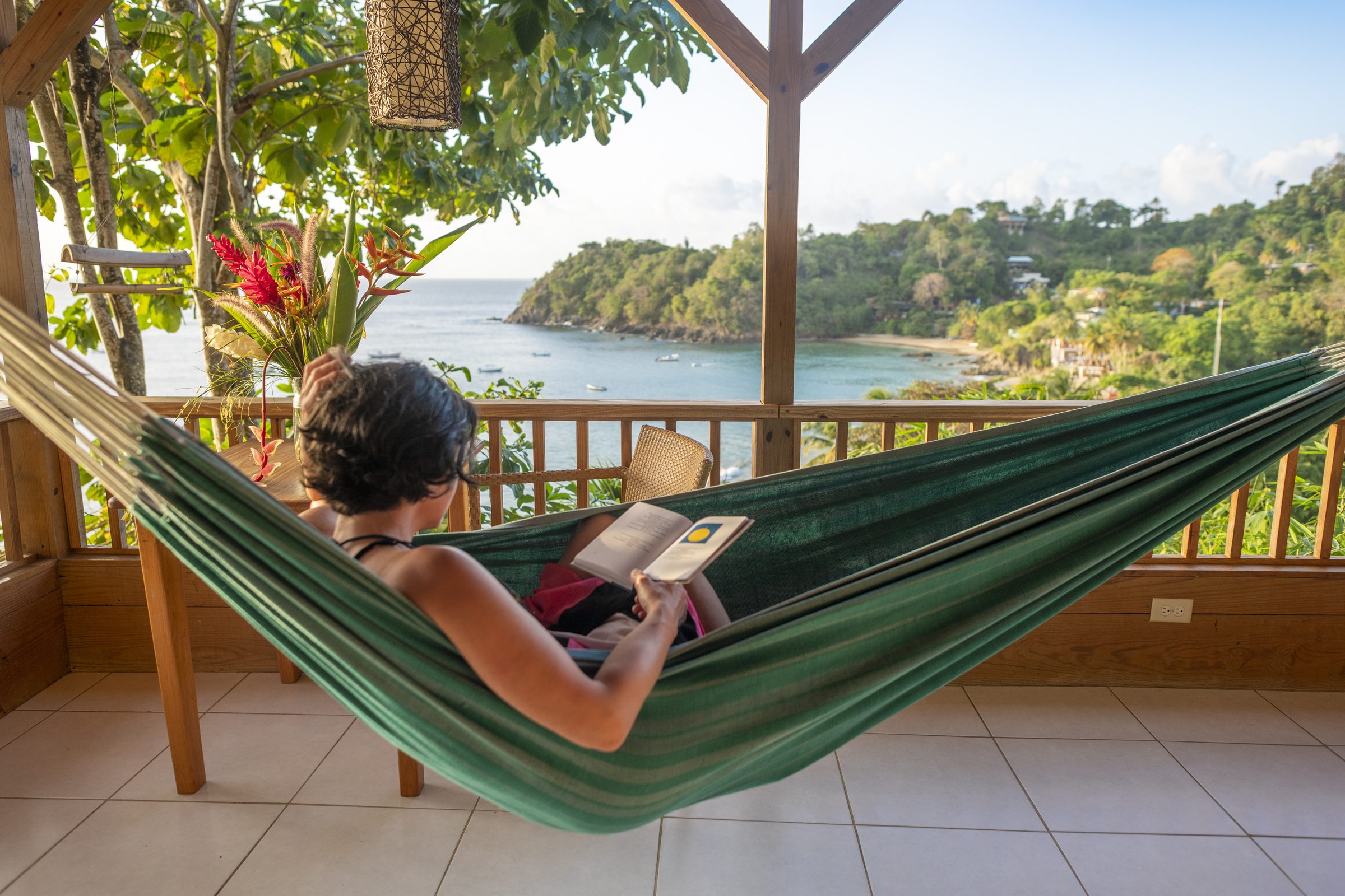 Person relaxing in a hammock overlooking Castara Bay, Tobago